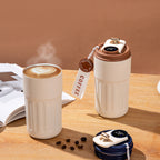 Two ceramic travel coffee cups with digital temperature displays on a wooden surface.