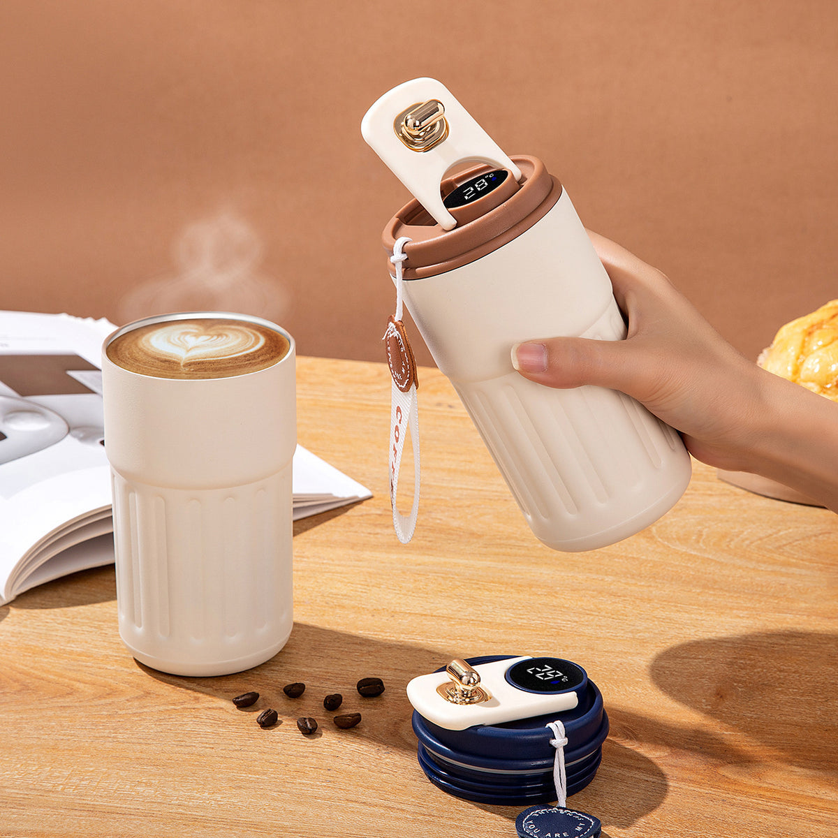 Hand holding a white Smart Insulated Coffee Cup with a coffee cup on a wooden table.