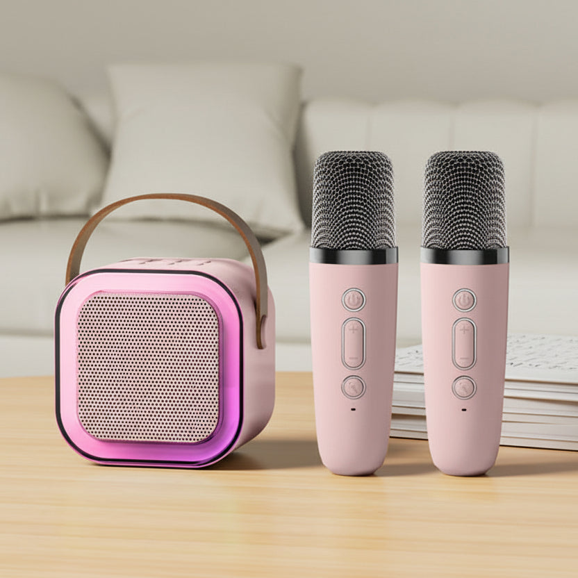 Pink portable speaker and two microphones on a wooden surface with a blurred background