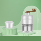 Manual ice cream maker set with a silver hand-crank machine, brown handle, and two green circular molds, shown on a light green background.